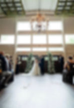 Tall white and greenery floral arrangements displayed at an indoor wedding venue