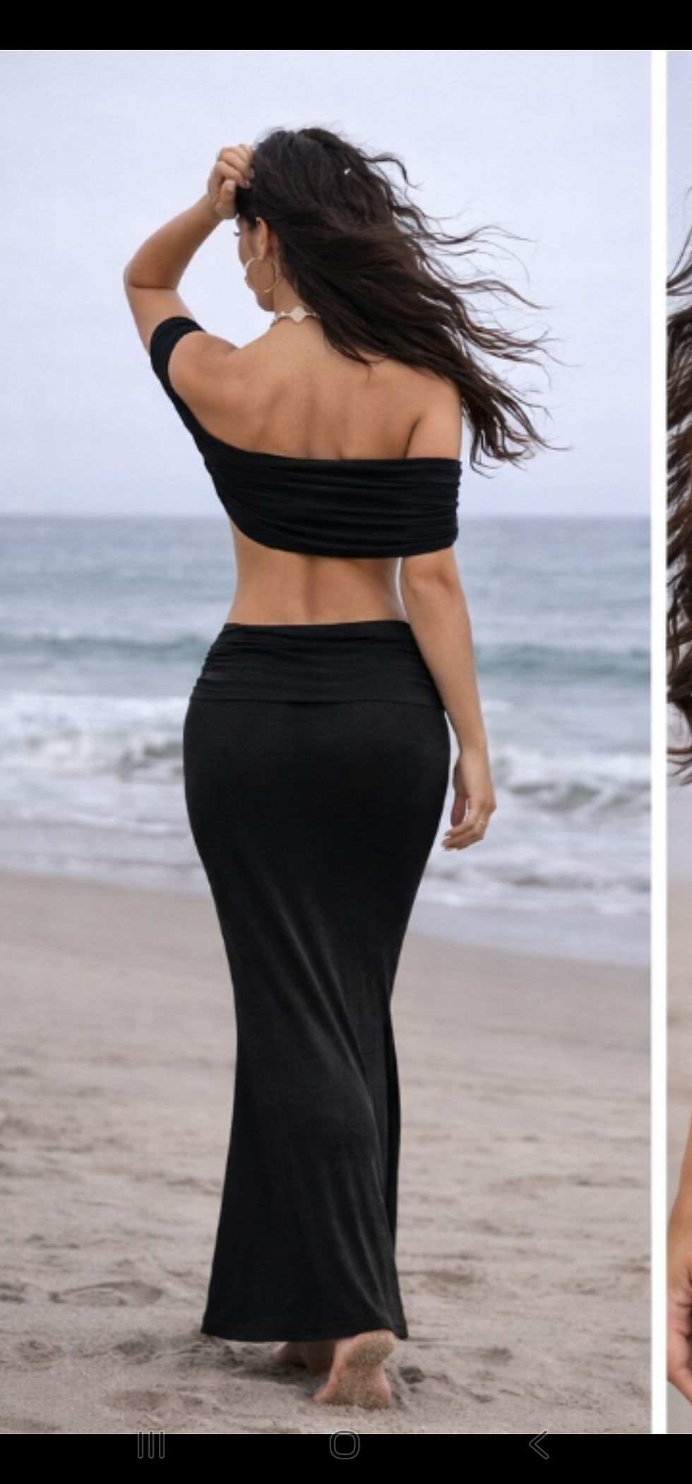 Woman wearing black beach co-ord set walking on sand.