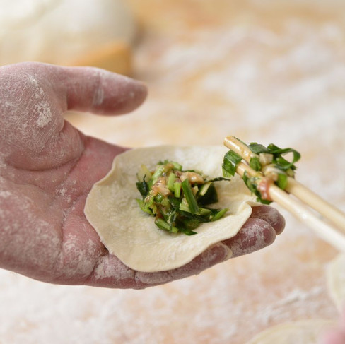 Using chopsticks to fill dumpling wrapper with pork and wild garlic