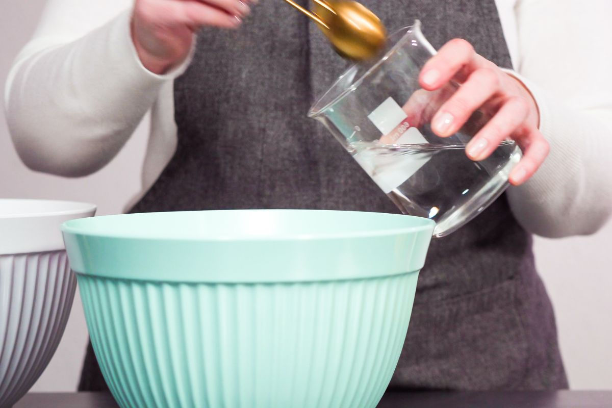 Adding water into blue bowl of royal icing