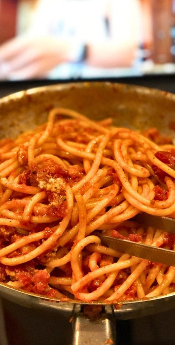 skillet of pasta being held to a computer screen