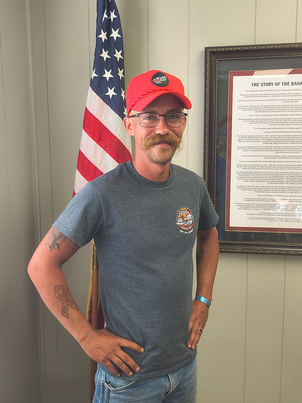 Man in a red hat standing by an American flag in Town