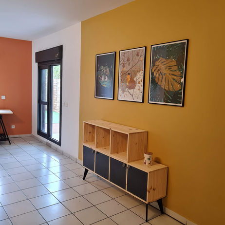Séjour modernisé avec mur jaune, mobilier bois et optimisation des volumes dans une case Tomi rénovée à Sainte-Suzanne par architecte d’intérieur 974.