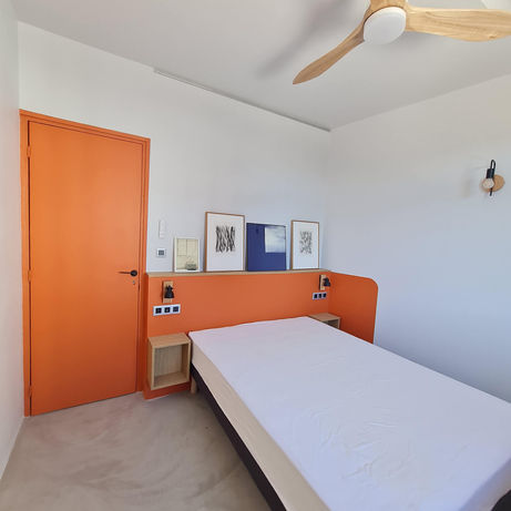 Chambre rénovée avec tête de lit maçonnée orange et rangements suspendus – appartement années 60 modernisé