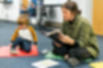 image of a female young adult reading to a little boy