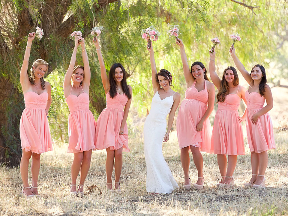 Bridesmaids holding flowers in air and wearing pink