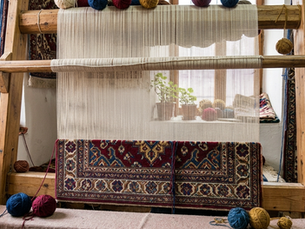 Traditional loom with a partially completed handmade rug displaying detailed patterns and colors