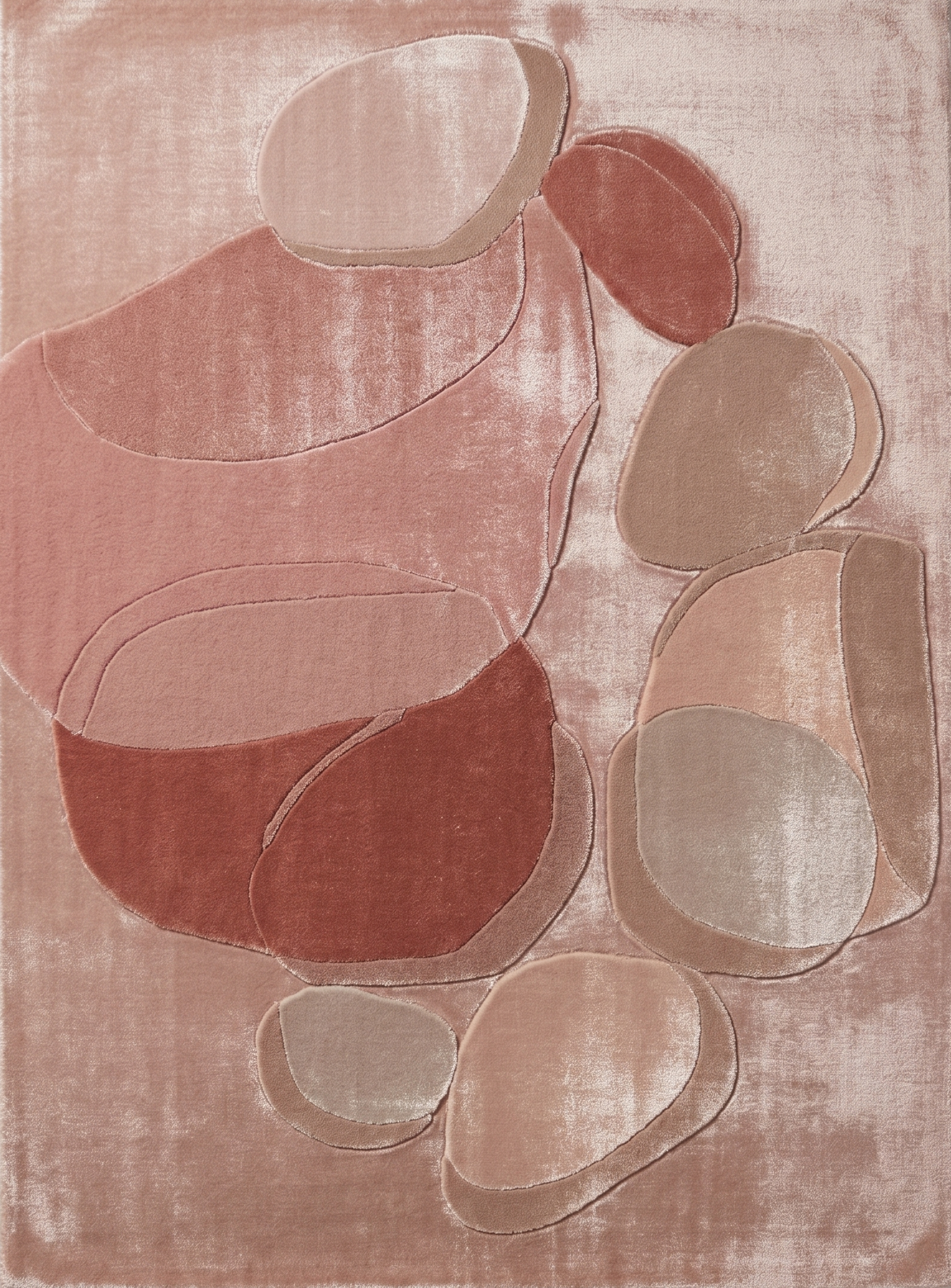 Overhead view of a hand tufted abstract pebble viscose rug with silky dusty rose and terracotta overlapping stone shapes.