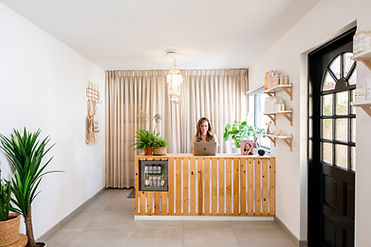 Lichte kapsalon met houten balie, planten en Muriël Emilie aan het werk