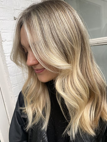 Vrouw met goudblond haar en lichte highlights kijkt omlaag