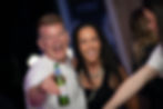 Man and woman laughing, man holding beer and pointing