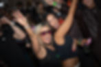 Two women cheering and dancing at a live house music dj set