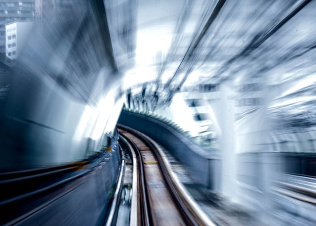 A train moving at speed through a curving tunnel, conveying the pace at which a complex ownership transition moves and the need for someone guiding it from the front.