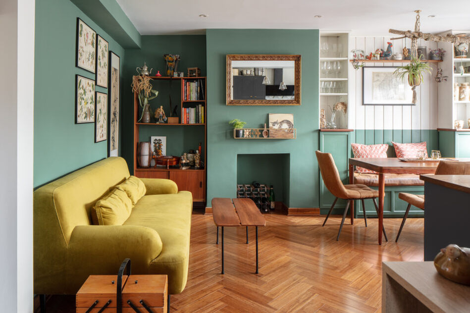 Mid-century inspired living room with green feature wall, parquet floor, and vintage furniture