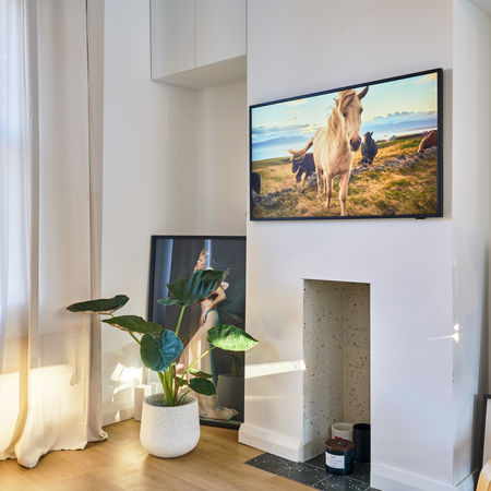 TV corner with tall windows, indoor plants and wall-mounted screen
