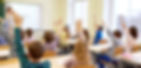 Children raising their hands in a classroom.