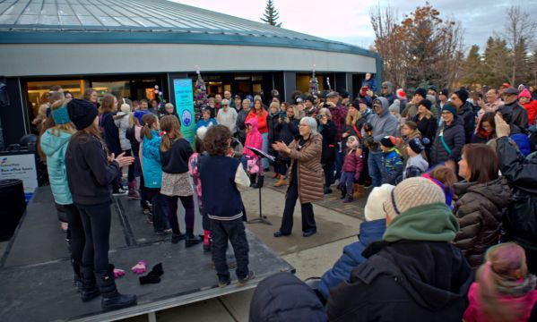 Crowd gathered outside for a community event where the Junior Choir is performing.