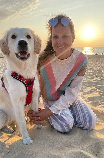 Golden Retrieverdame mit Frau mit Herz Sonnenbrille, lächeln in die Kamera vor Sonnenuntergang am Strand