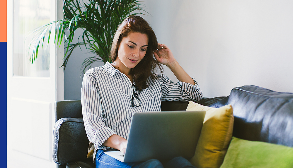 A woman sitting on a couch working remotely