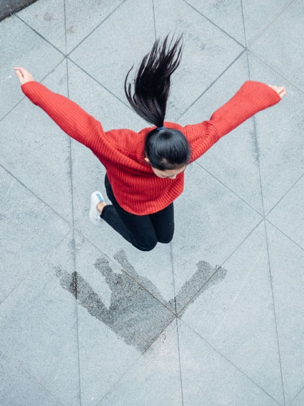 Picture of a girl with long black hair jumping in the air.