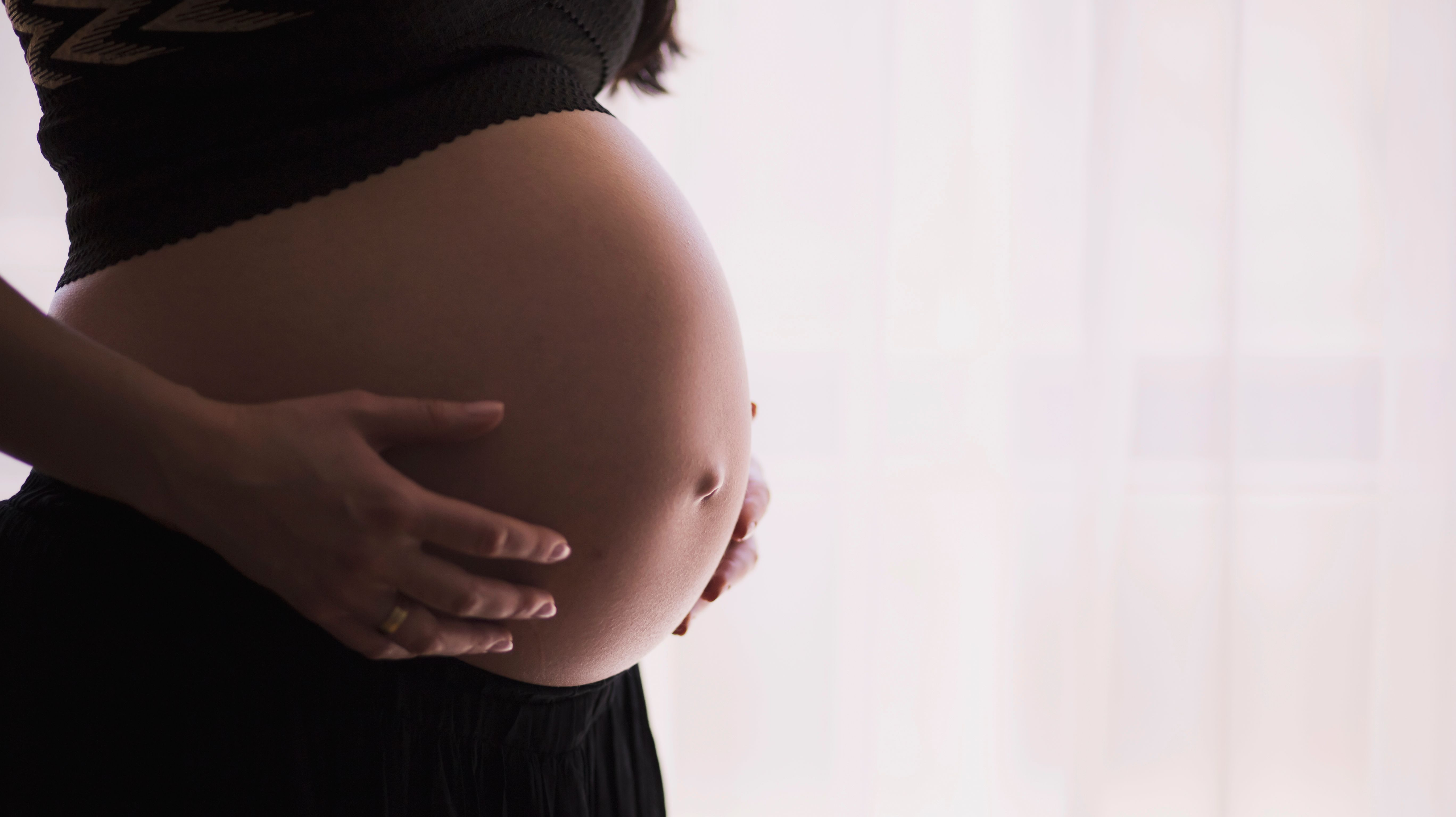 A tender moment captured: a mother-to-be gently cradles her growing belly, filled with anticipation and love for the new life she is nurturing.