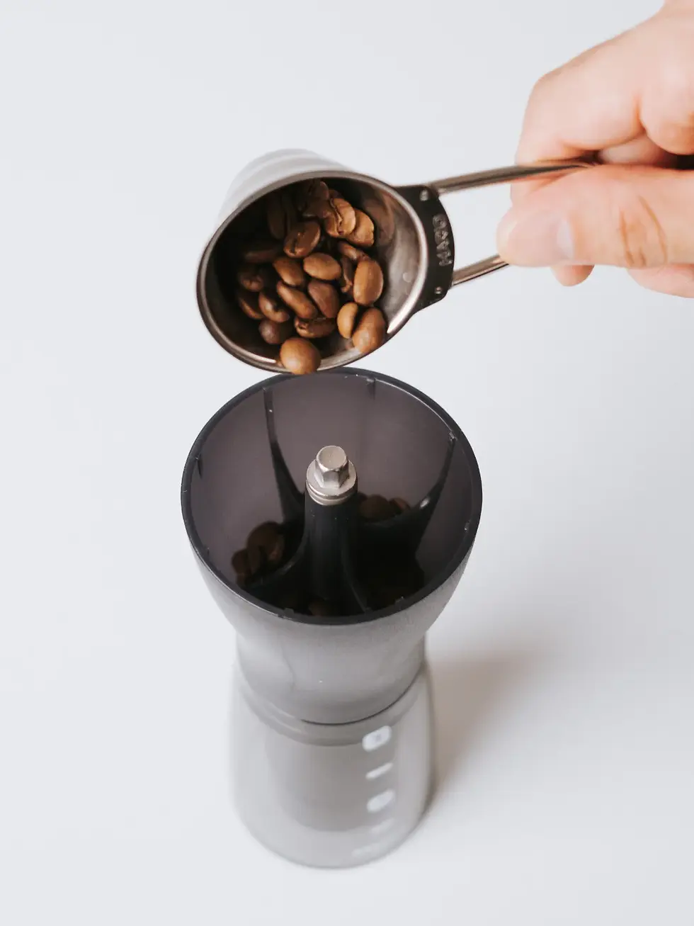 coffee scoop pouring coffee beans into Hario Grinder