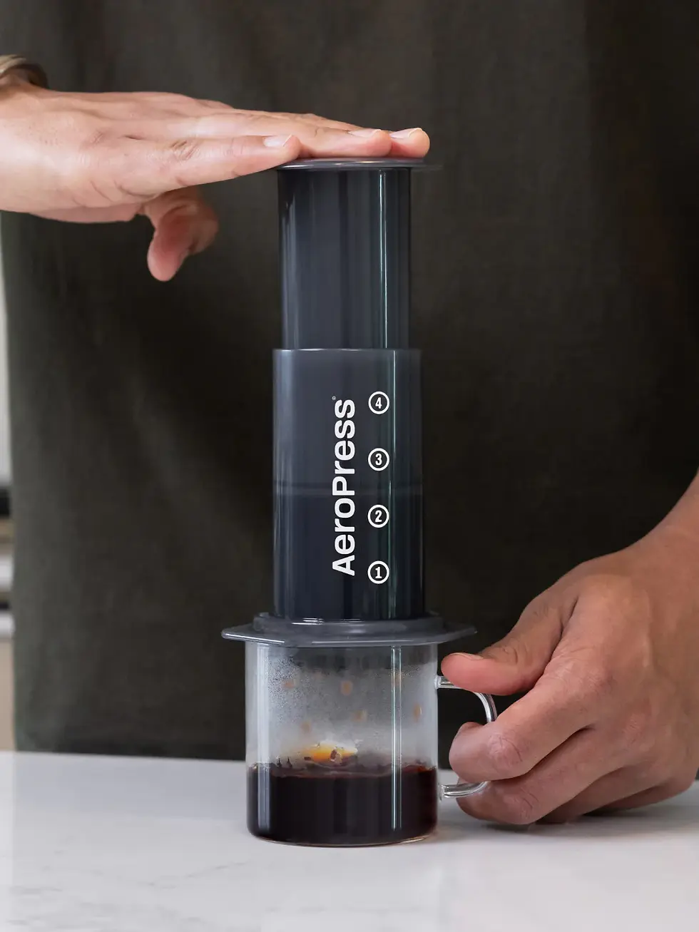 hand pushing AeroPress coffee maker into cup
