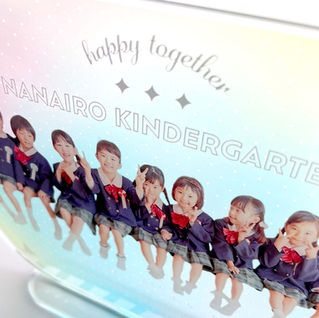 “happy together…” と “NANAIRO KINDERGARTEN” のロゴ、園児の集合写真が入ったSPRING POPシリーズのアクリルスタンド拡大