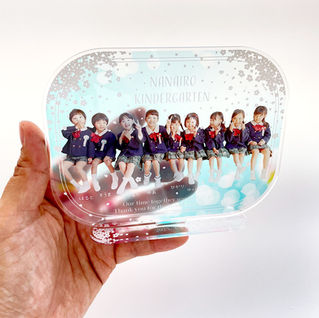 手に持ったSAKURAシリーズの卒園記念アクリルスタンド。園児の集合写真と桜の背景が際立つ優しいデザイン