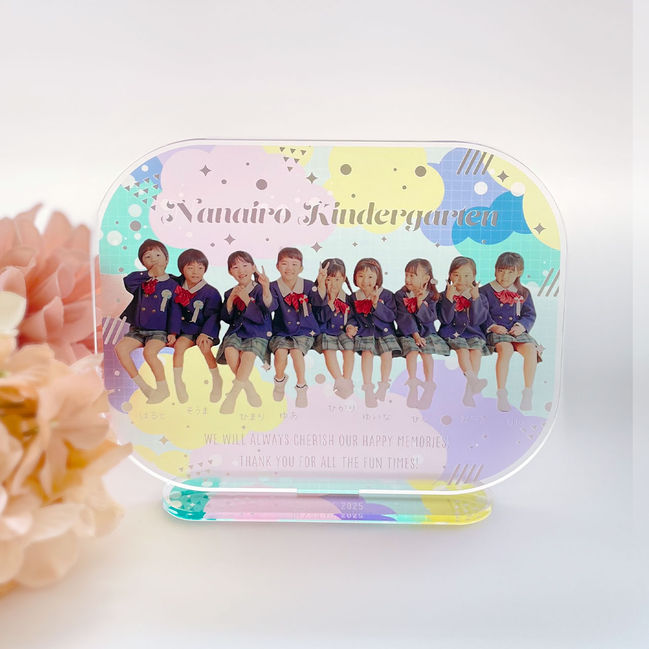 PUFFINシリーズ・集合写真タイプのアクリルスタンド。お花と一緒に飾られた、園児たちが並んだ卒園記念フォトスタンド