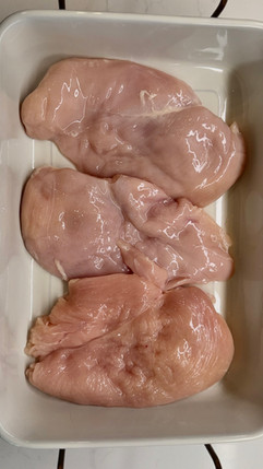 Raw chicken breasts in a white baking dish