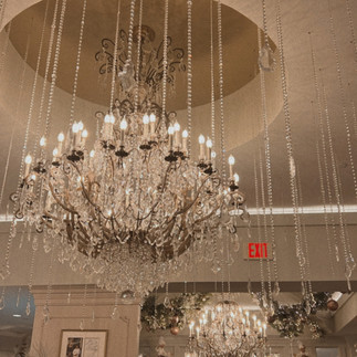 A large fancy chandelier hanging from the ceiling of a fancy French restaurant full of crystals