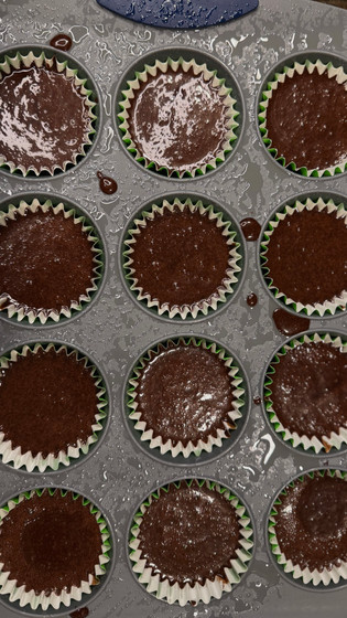 Chocolate cupcake batter poured in a cupcake pan with cupcake liners in it