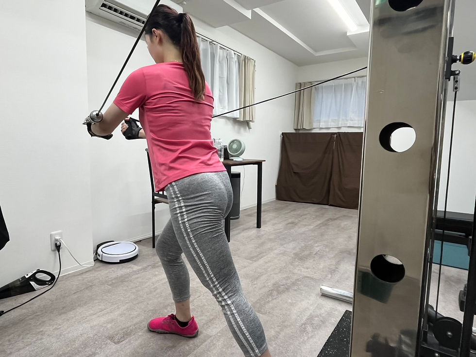 パーソナルジムでケーブルマシンを使ってトレーニングする20代女性の後ろ姿