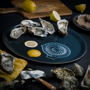 Plateau d'huîtres fraîches ouvertes avec citrons et couteau à huîtres.