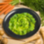 Plateau de service rond noir avec une salade verte imprimée en trompe-l'œil posé sur une table avec des légumes autour