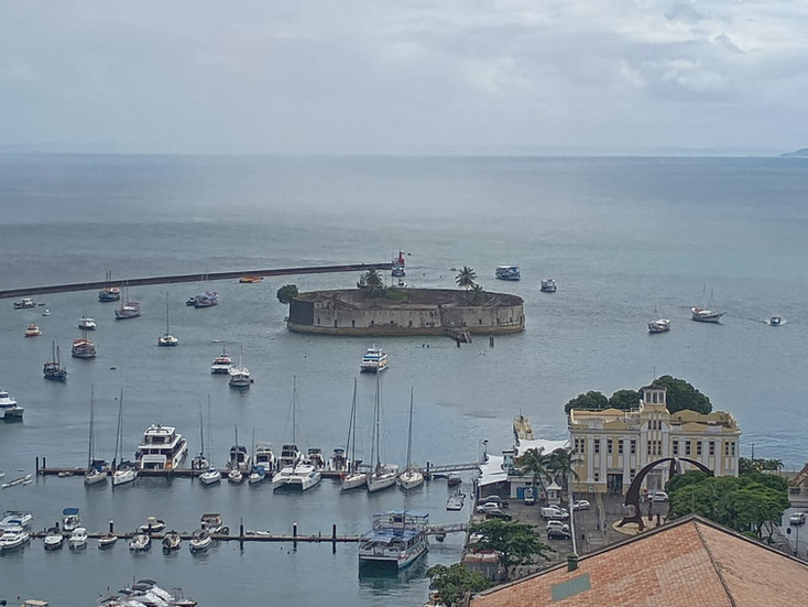 A hazy photo of a boat-dotted sea with a round stone fort in the middle