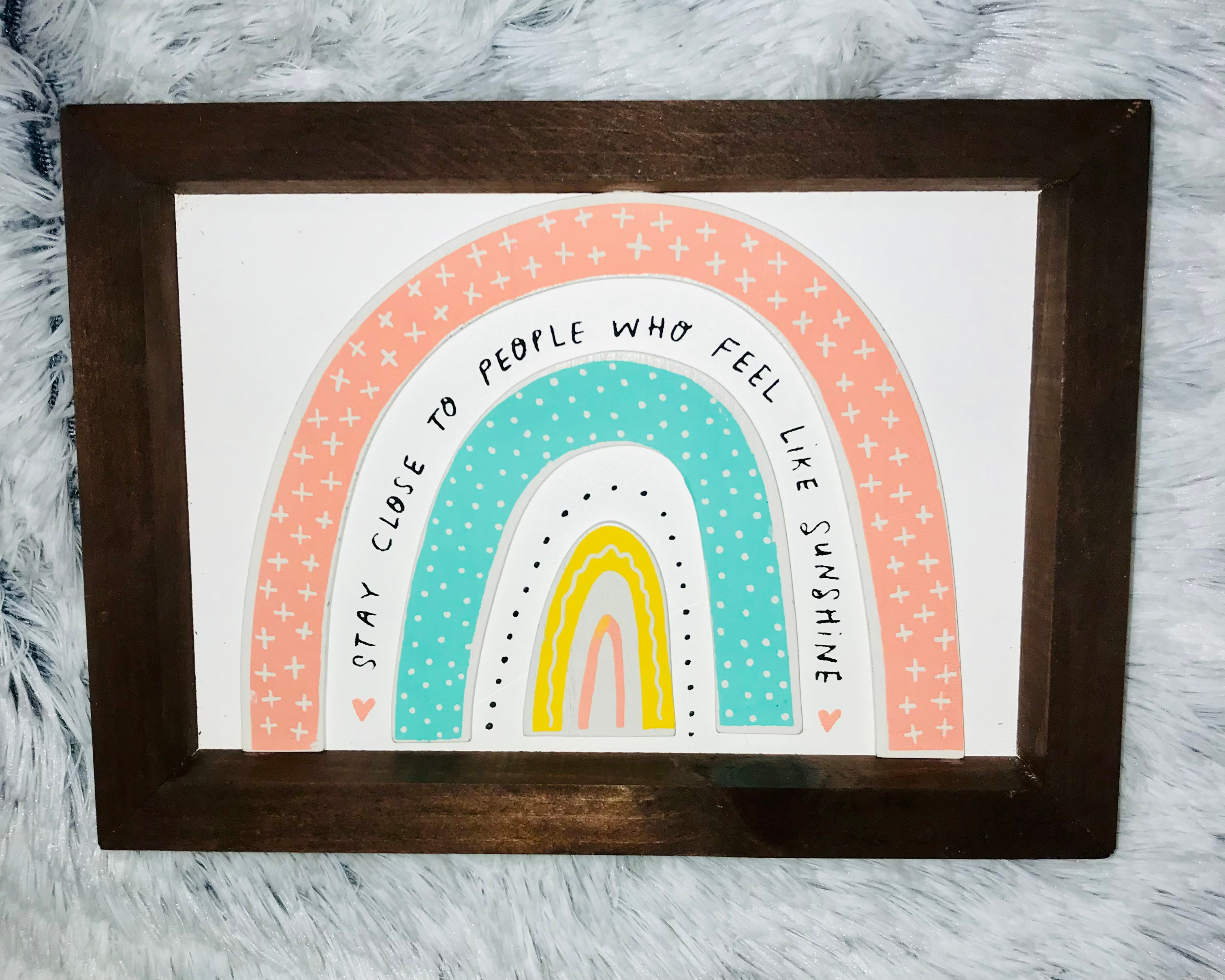 Rainbow art on a wall with text: Stay close to people who feel like sunshine.