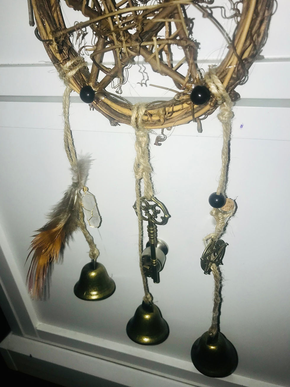 Thumbnail: Woven dream catcher with feathers, bells, and keys hanging against white background.