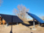 Two solar panels set up in a yard angled towards the sun.