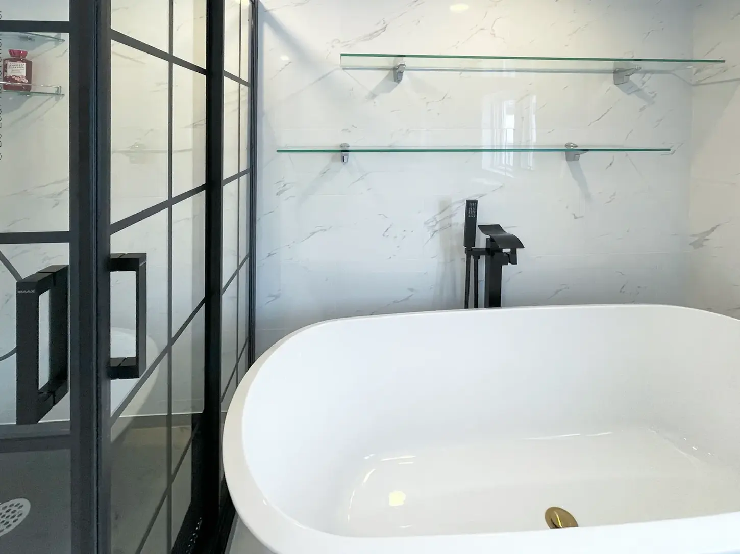 bathroom renovation white tub black floor fixture glass shelves