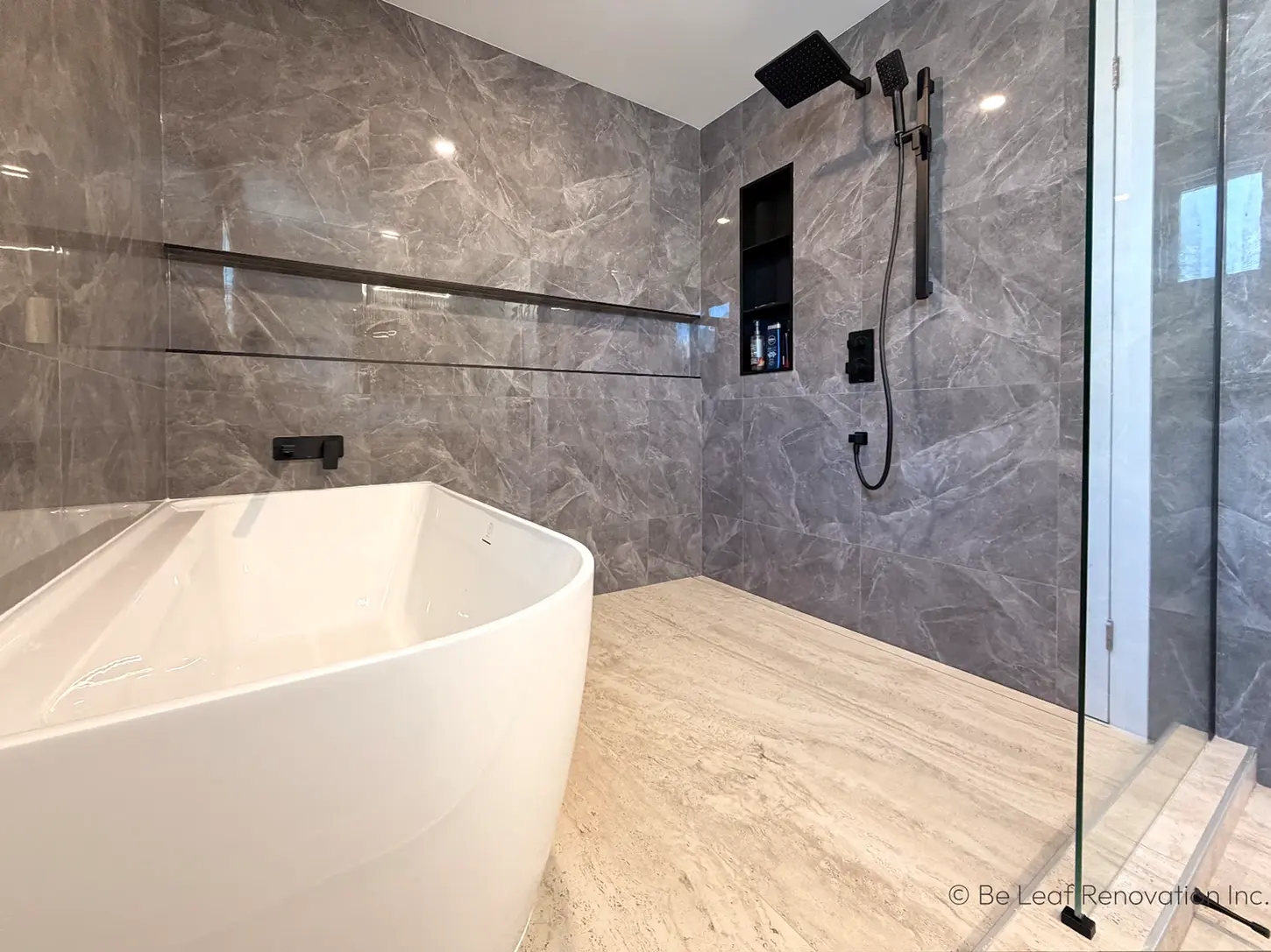 Freestanding tub against gray marble tile walls.