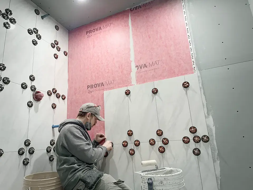 Beaverbrook master bathroom renovation worker installing large format wall tiles in shower enclosure.