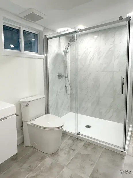 White bathroom vanity and toilet near glass shower
