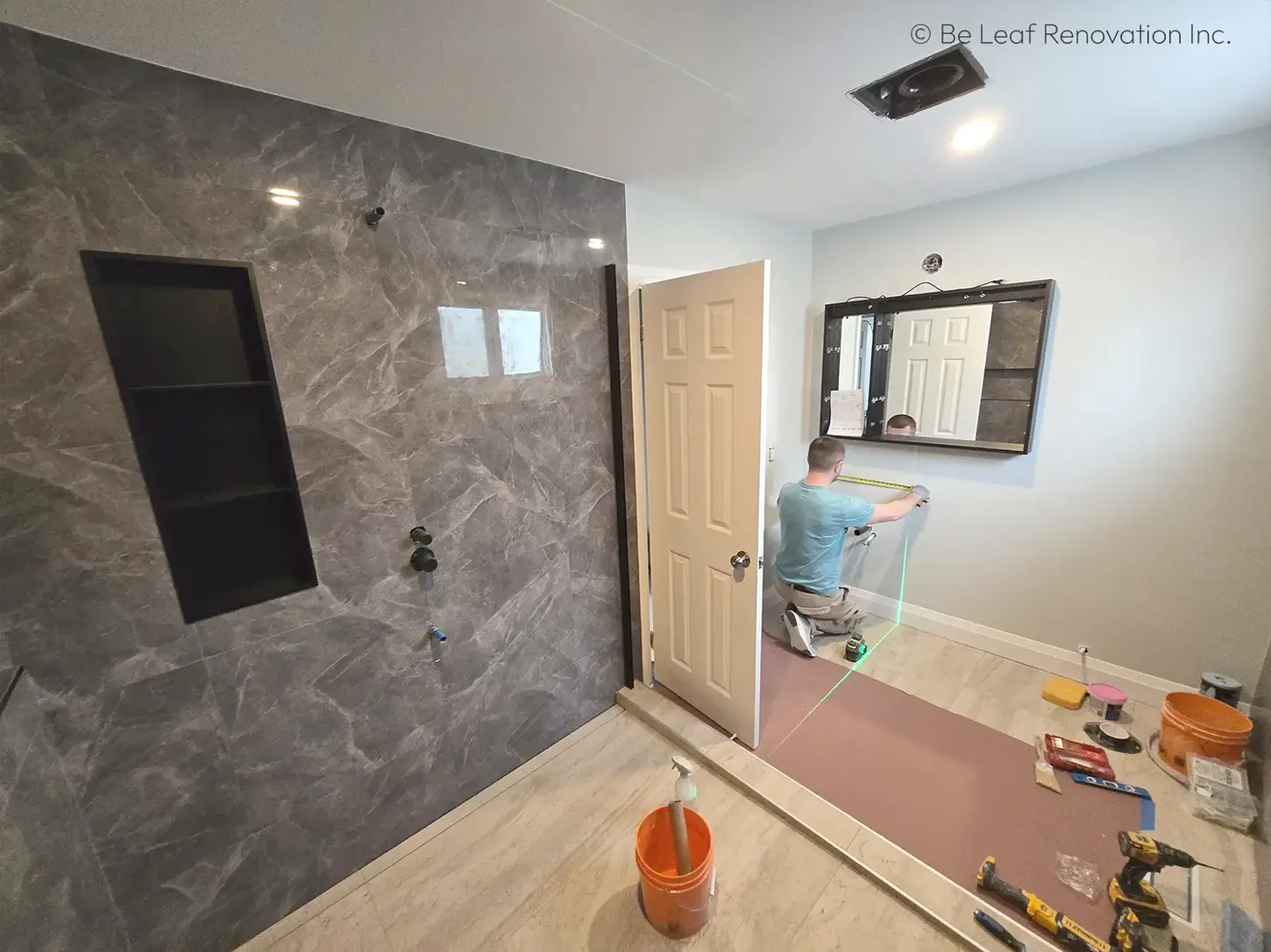 Contractor using laser level for vanity mirror.