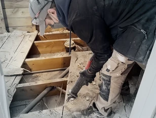 Worker uses reciprocating saw on subfloor during bathroom remodel