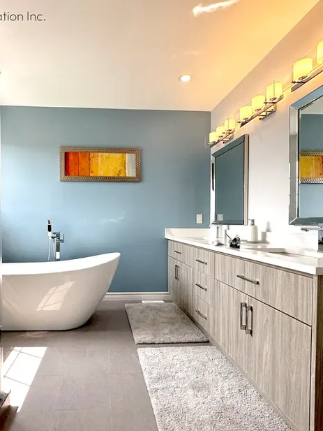 Master bathroom showing freestanding bathtub, blue wall, long wood vanity, and two mirrors
