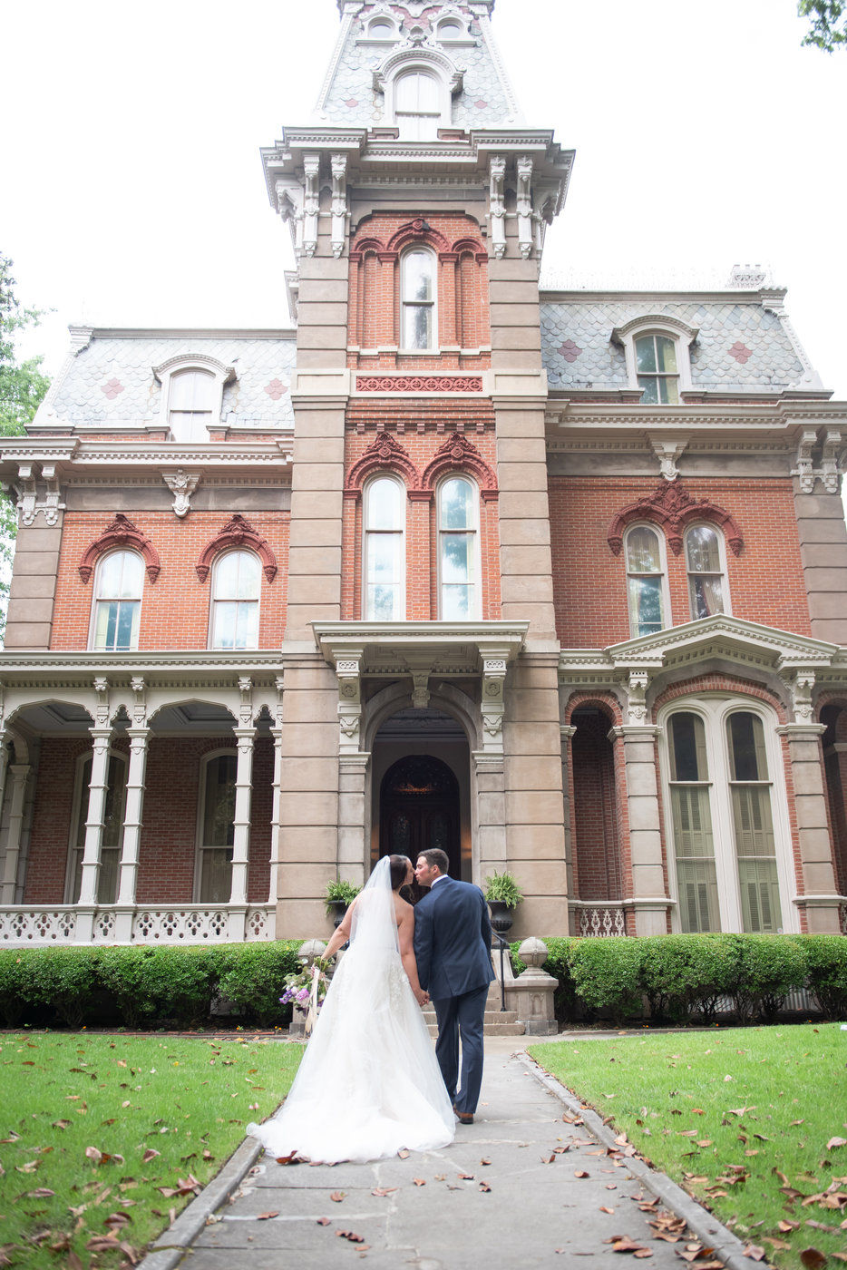 Bride and Groom kissing in front of mansion