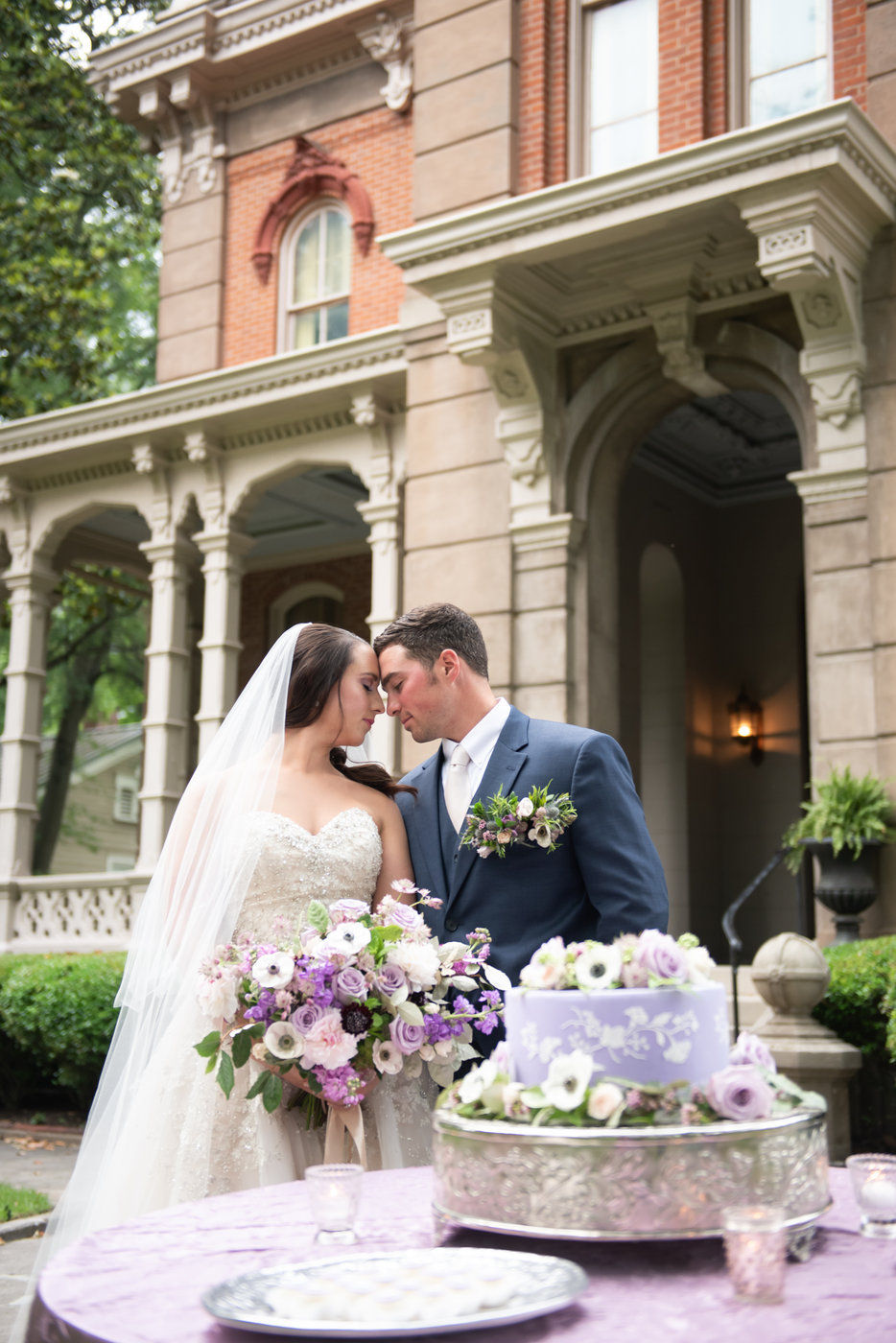 Bride and groom standing with purple wedding cake