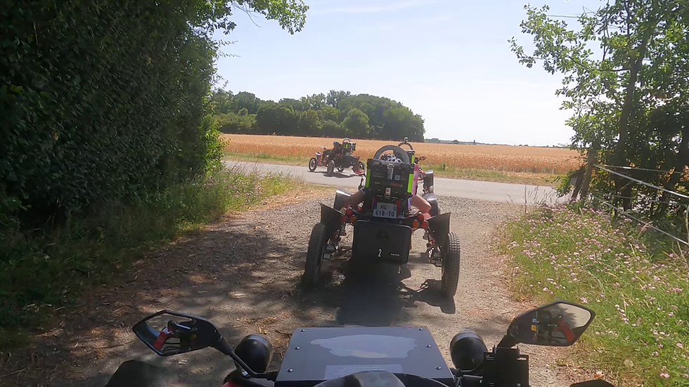 Plusieurs Swincar électriques sur un chemin de terre, groupe d’adultes casqués en pantalon long, haie et champ à Tuffalun